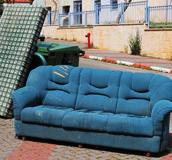 Vieux canapé bleu et autres meubles laissés en bordure de route